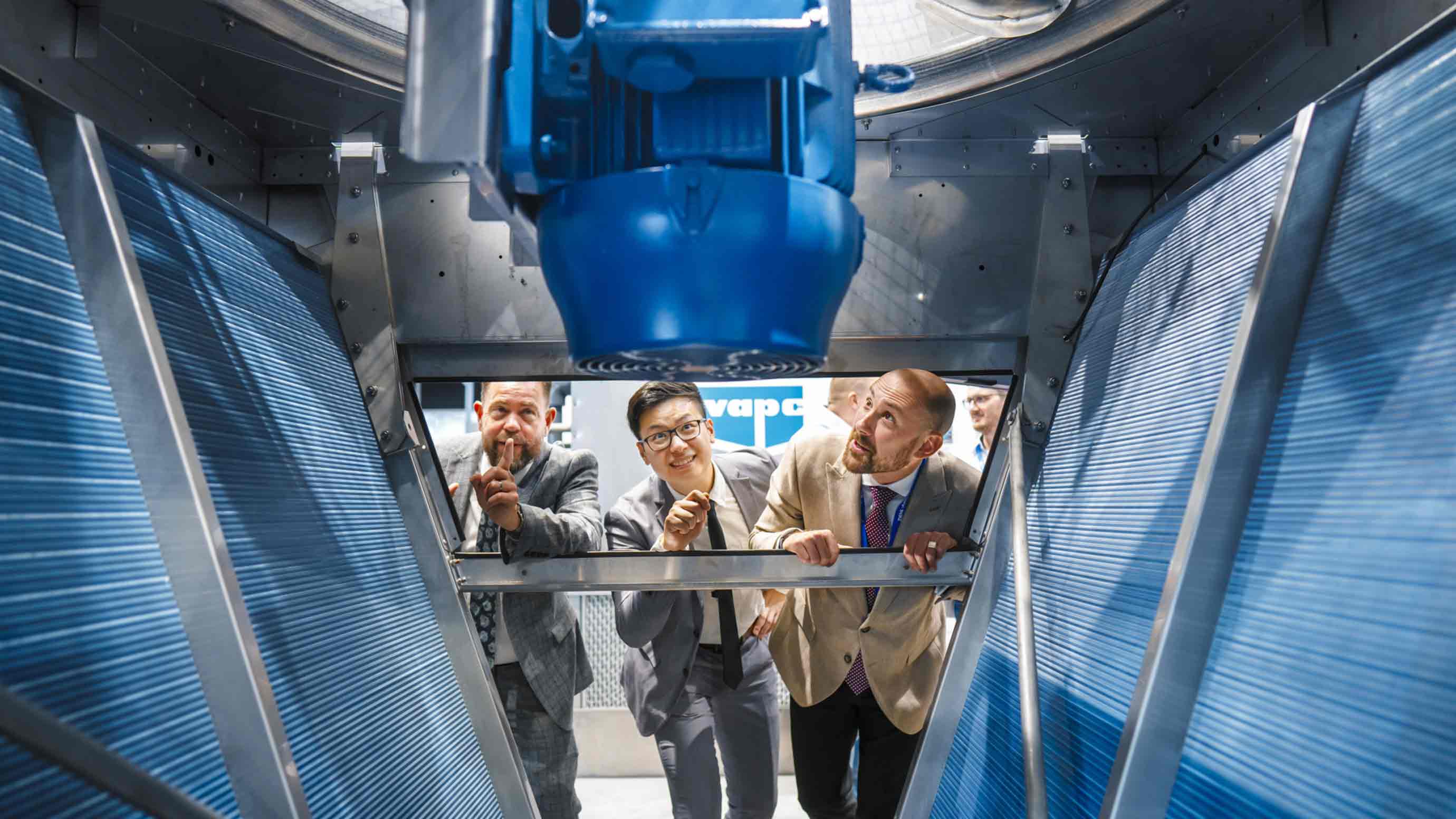 Three trade fair participants look into a refrigeration system